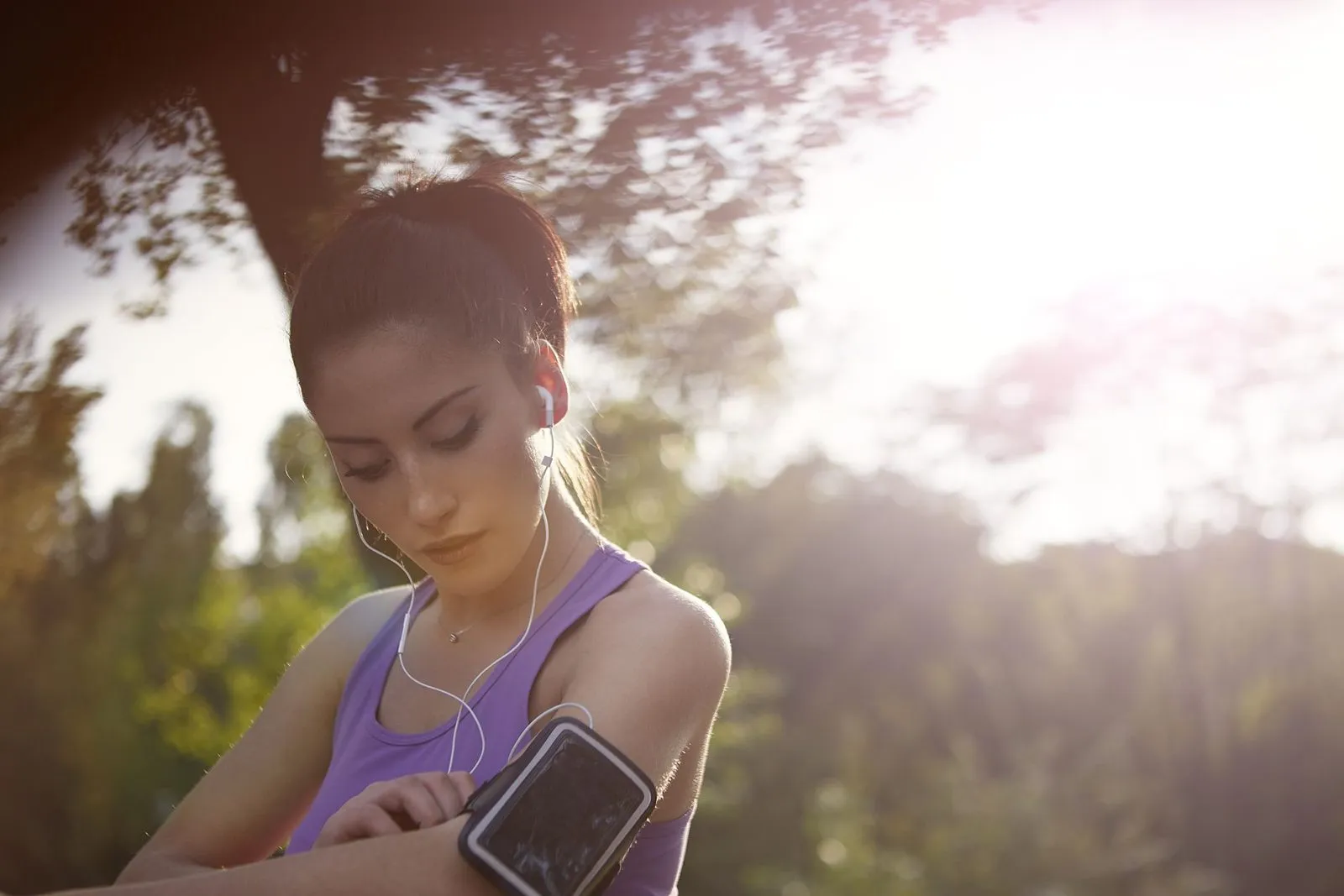 Kvinna som kontrollerar sitt handled med en telefon i ett armband på överarmen