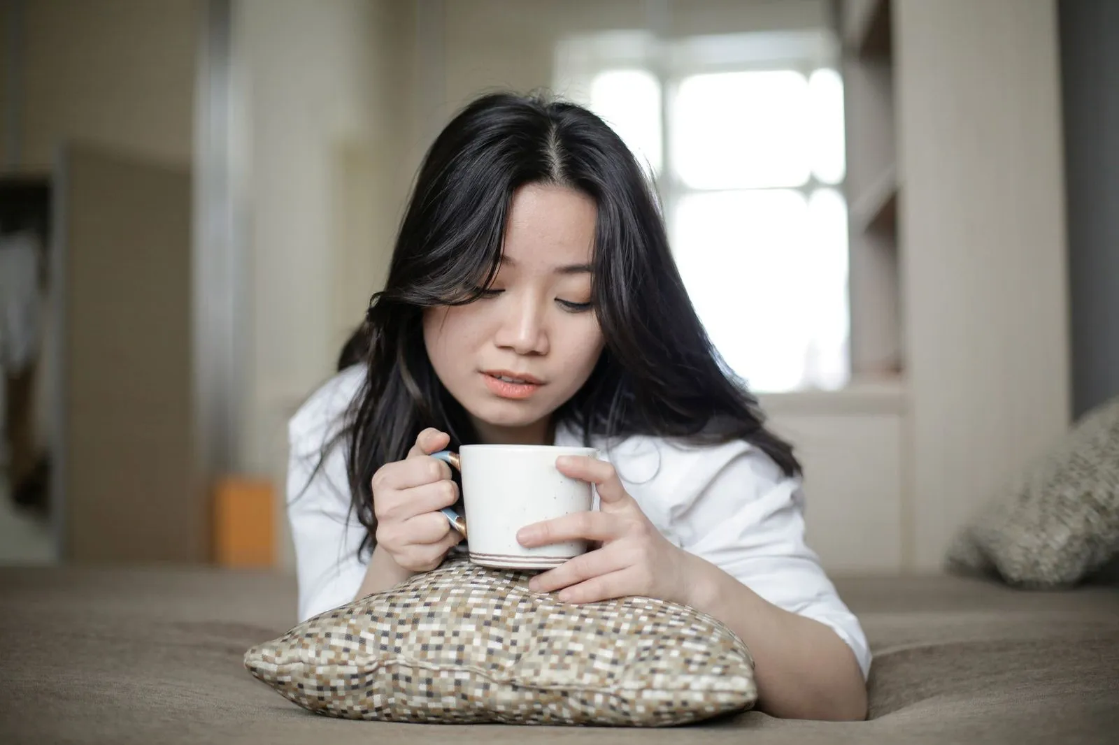Kvinna som sitter med en kopp kaffe i famnen