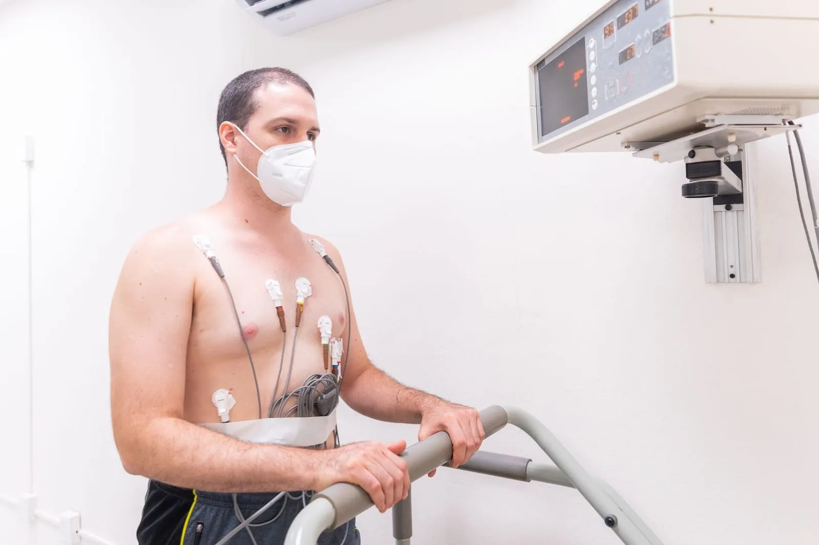 Man med elektroder på bröstet gör ett belastningstest på löpband på en klinik.