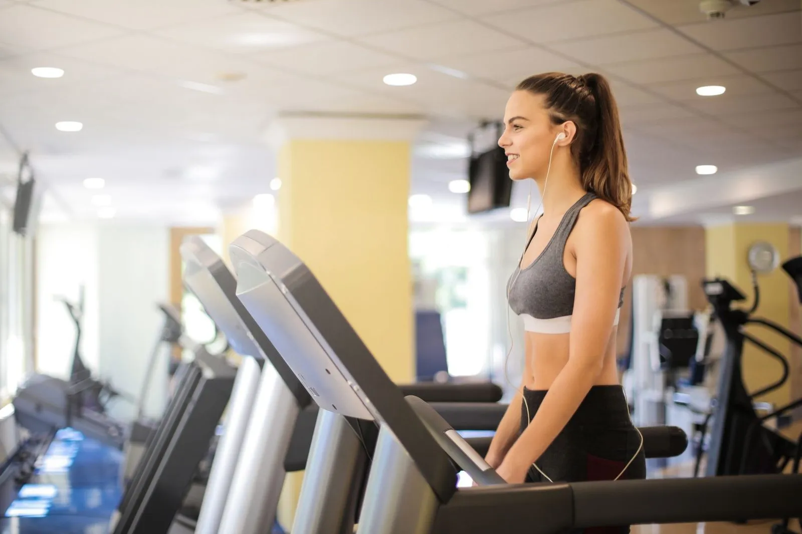 Kvinna som springer på ett löpband på ett gym
