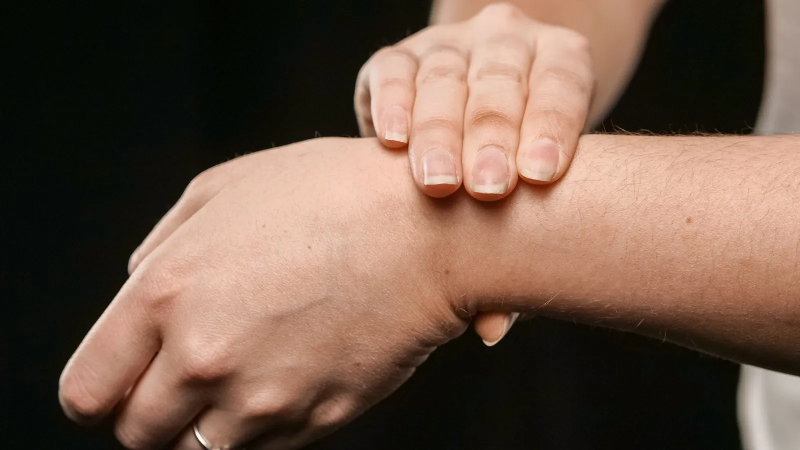 Två fingrar som trycker mot insidan av en handled för att känna pulsen.