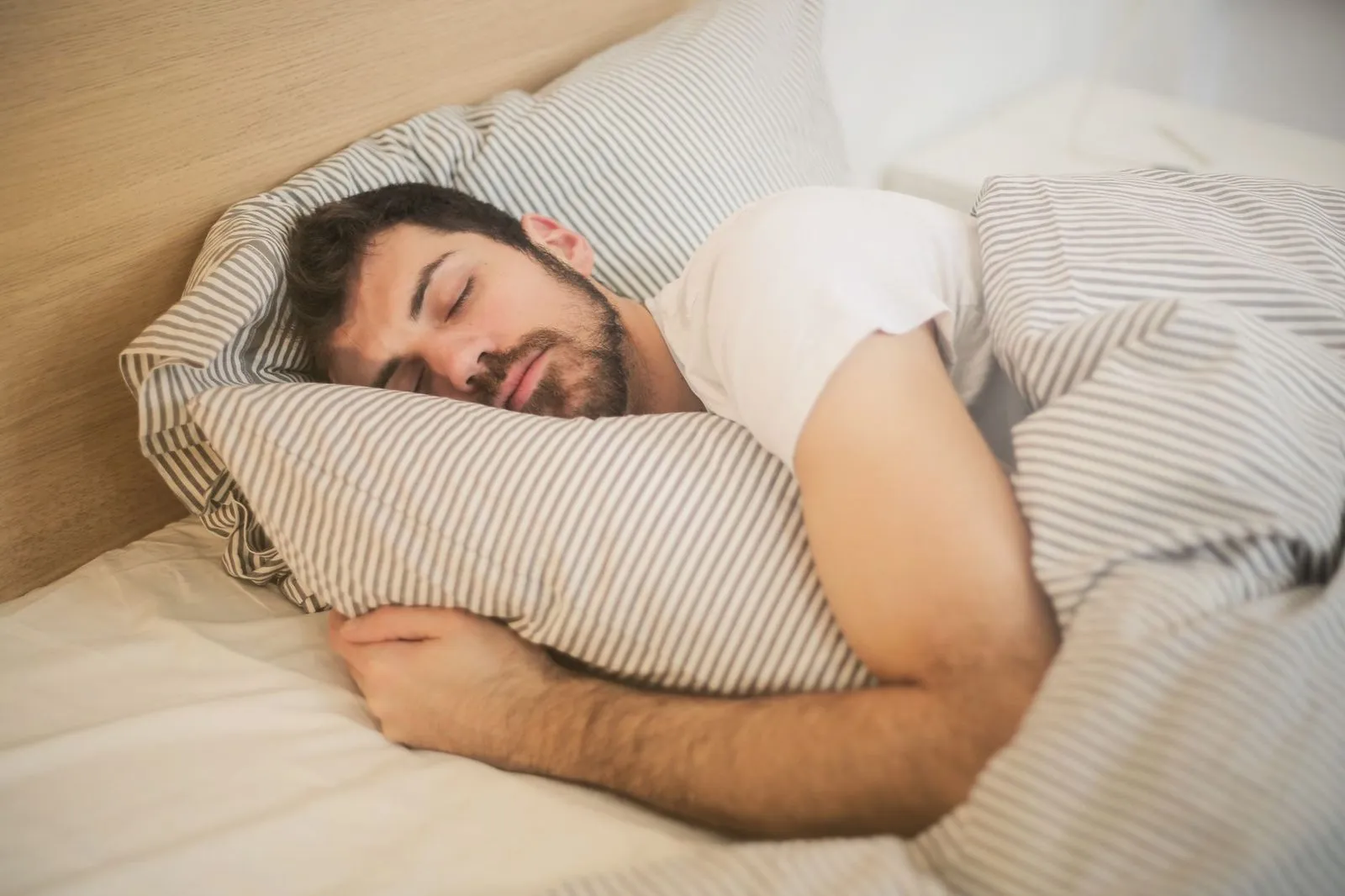 Man som sover på sidan i ett dagsljust sovrum.