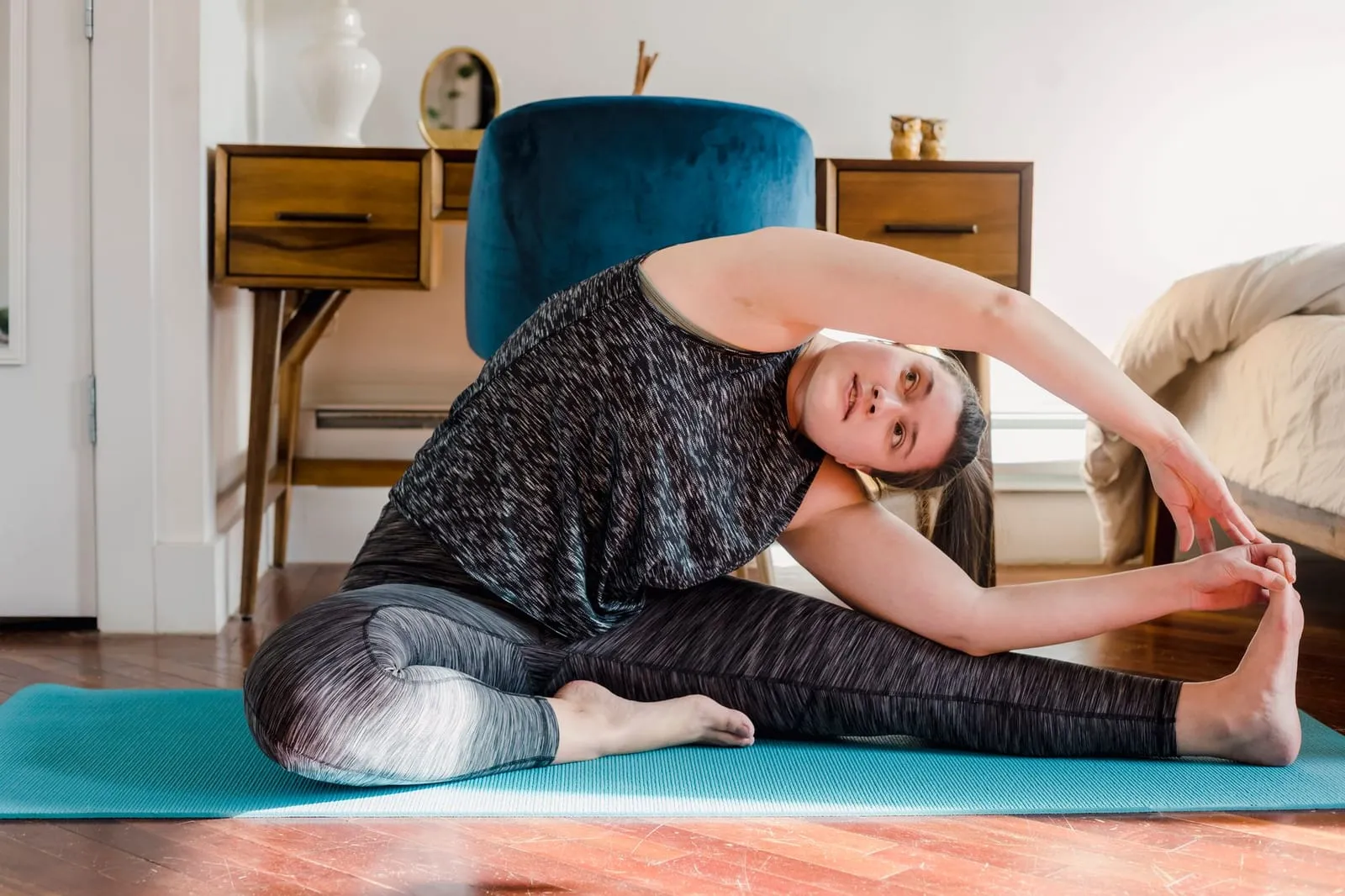 Kvinna sträcker ut sig på en yogamatta hemma.