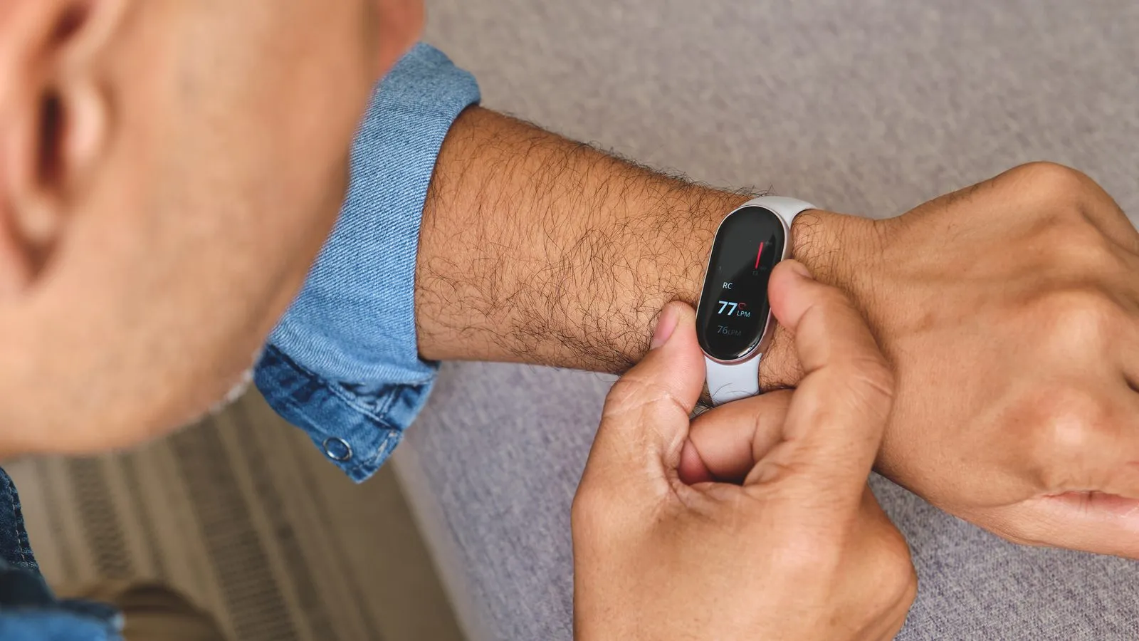 Man trycker på ett vitt fitnessarmband med liten skärm som visar puls på handleden